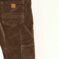 Braune Cordhose mit aufgesetzter Tasche, Detailaufnahme des Textils mit Fokus auf Struktur und Labelpatch.