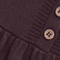 Nahaufnahme eines dunkel gestrickten Stoffes mit Holzknöpfen auf einem schwarzen Kleidungsstück.